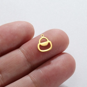 Golden gourd-shaped stainless steel pendant held between fingers on white background