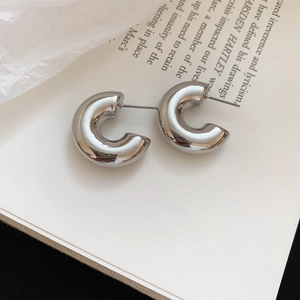 Macro shot of silver-tone C-shape metallic stud earrings with a polished mirror finish