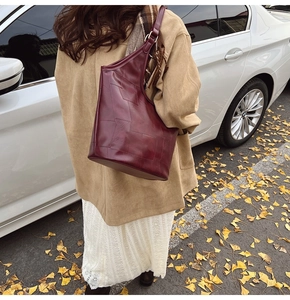 Detailweergave van de dieprode lederen shopper met uniek patchwork op een straatfoto