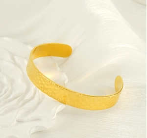 Détail du bracelet manchette doré en C avec texture martelée et bordure perlée