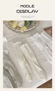 Detailed view of women's socks with bow patterns and ruffled edges on white cotton fabric