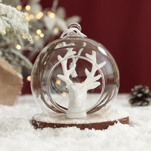 Clear glass Christmas ornament with white reindeer head, wooden base, and festive snow scene