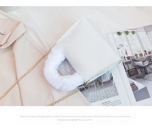 Detailed view of white faux fur handle and smooth leather texture on a small chain bag