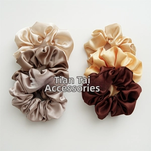 Detail of six assorted brown satin scrunchies set with silky luster on white background