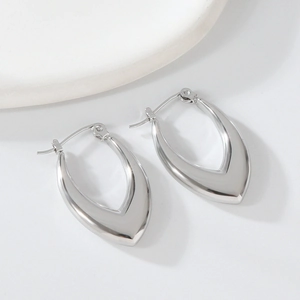 Close-up of minimalist irregular teardrop silver earrings on white stones