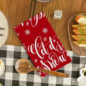Detail of red microfiber Christmas tea towel with white Let it snow text and snowflake design