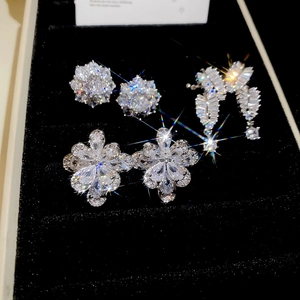 Macro view of three silver zircon flower earrings and tassels on a black velvet display