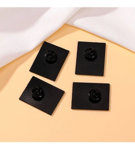 Close-up of black alloy brooch backings with secure rubber pin backs on textured fabric