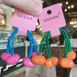 Detail of colorful elastic hair ties with cherry charms and branded pink card packaging