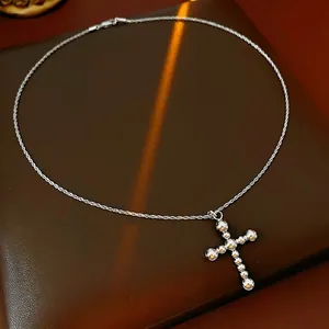 Collier avec pendentif croix en perles argentées sur boîte en cuir avec lumière