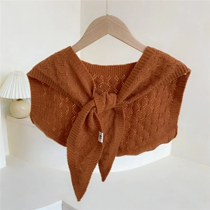 Knitted warm shawl wrap in rust red featuring hollow patterns on a wooden hanger