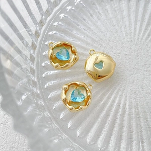 Detail of three 14k gold-plated circular pendants with inlaid blue heart-shaped zircons