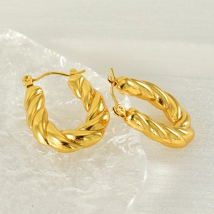 Polished gold U-shaped twisted hoop earrings displayed on a frosted glass tray