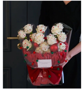 Detail of white rose bouquet with festive red pom poms and large red bow wrapping