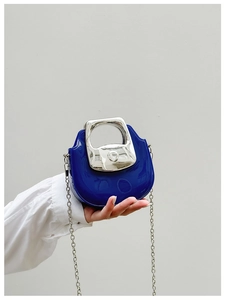 Detail of blue mini crossbody bag featuring a round silver metal handle and chain strap