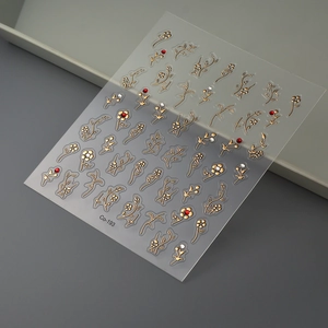 Macro view of gold embossed flower nail stickers with red rhinestones on a grey background