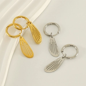 Detail of gold and silver stainless steel hollow wing earrings on silk fabric background