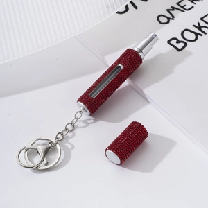 Macro shot of dark red rhinestone perfume bottle with viewing window and silver keychain