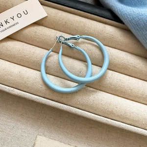 Close-up of matte sky blue round hoop earrings placed in a white jewelry tray