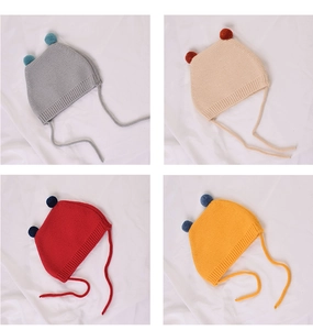 Detail of knitted baby hats with pom-poms in gray, beige, red and yellow colors