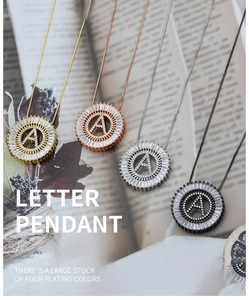 Detailed view of four round letter A pendants with cubic zirconia in various metal finishes