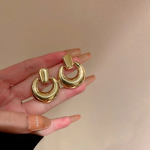 Detailaufnahme von eleganten goldenen Creolen mit glatten, geometrischen Anhängerkurven