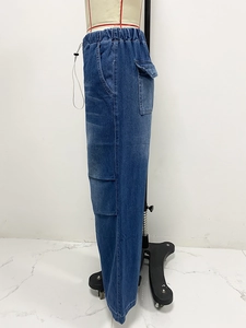 Detail of blue cargo denim jeans featuring large side flap pockets and washed finish