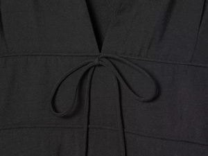 Detailed macro view of the black V-neck dress featuring a soft knitted tie-up bow design