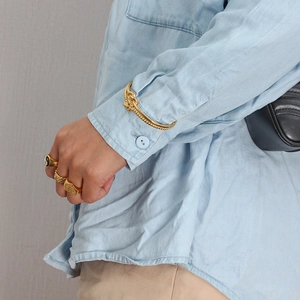 Close-up of a stacked gold jewelry set featuring a twist bangle and vintage rings