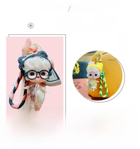 Cartoon doll keychain with black glasses and woven strap shown on a yellow bag