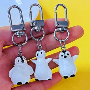 Detailed view of three cute 3D resin penguin keychains with silver metal clips