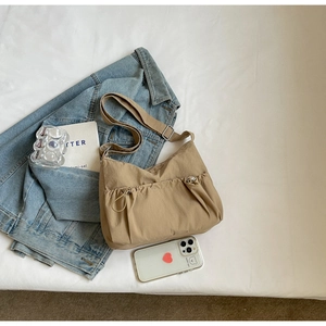 Flat lay detail of a khaki nylon crossbody bag with pleated pockets on a white background