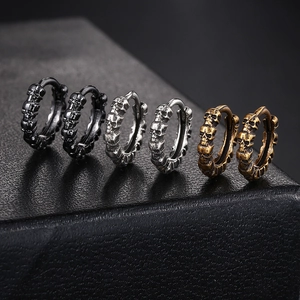 Gothic punk skull earrings in black, silver and bronze on textured leather display
