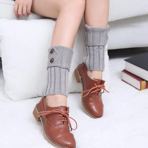 Detailed texture of grey knit leg warmers with buttons paired with brown leather shoes