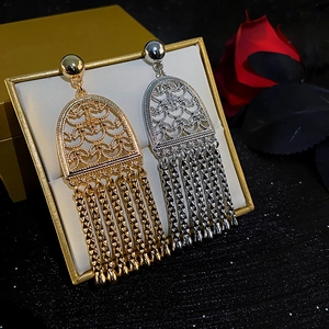 Detail of luxury long fringe earrings with hollow arch design and golden tassel texture