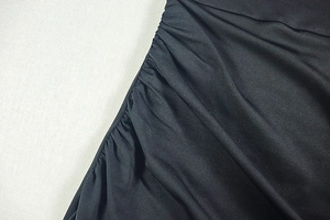 Detail of elegant black dress showing ruched fabric texture and pleated craftsmanship
