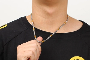 Detailed shot of two-tone braided silver and gold chain necklace on male model
