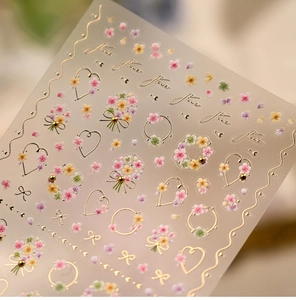 Macro detail of French floral nail stickers with gold foil accents and floral patterns