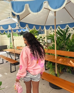 Outdoor back view of a pink letter print sweatshirt styled for a casual vacation look