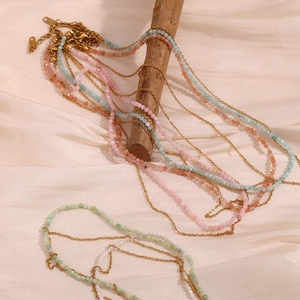Detailed shot of multi-layered gold chains with colorful beads on a silk background