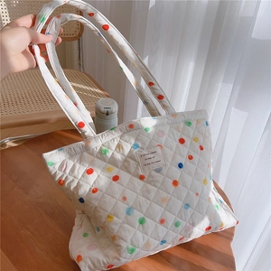 Close-up of quilted white tote bag with colorful polka dots and vintage fabric label