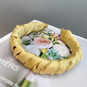 Detailed view of yellow satin pleated headband with elegant twisted silk texture