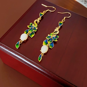 Dettaglio macro di orecchini a pavone in smalto placcati oro 14K con perle di giada