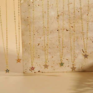 Macro detail of gold star pendants with colorful zircon stones on textured stone