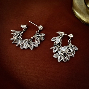 Silver leaf tassel earrings with sparkling zircon crystals on dark textured fabric background