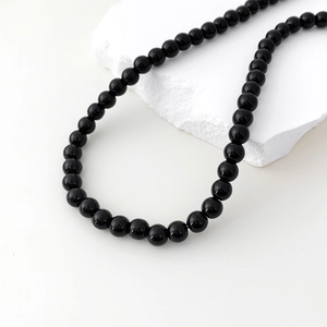 Detail of elegant black agate beaded necklace on minimalist white background
