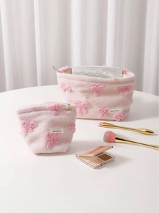 Pink plush cosmetic bag set with decorative bows and sleek gold metal zipper closure