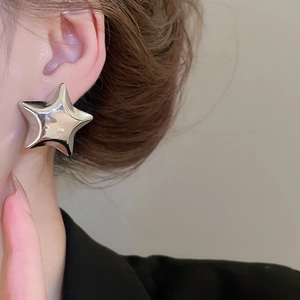 Close-up of model wearing large polished silver star stud earring with a glossy finish