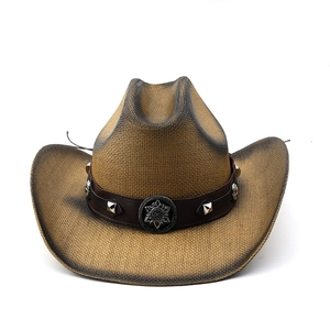 Détail d'un chapeau de paille de style western avec ruban cuir et insigne étoile