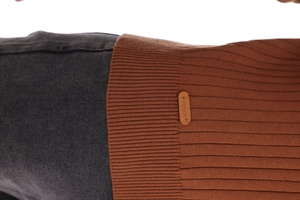 Detail of dark brown ribbed knit sweater with leather brand patch on the lower hem